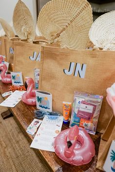 some pink flamingos are sitting on a table with straw hats and other items around them