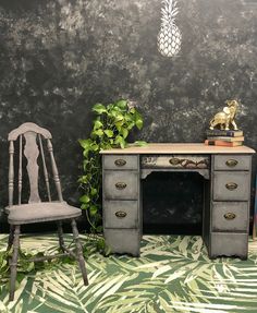 an old desk with a chair next to it and a pineapple on the wall