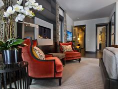 a hotel room with a bed, chairs and flowers in vases on the table