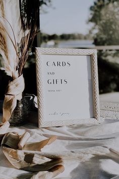 a card and gifts sign sitting on top of a table next to a vase with dried flowers