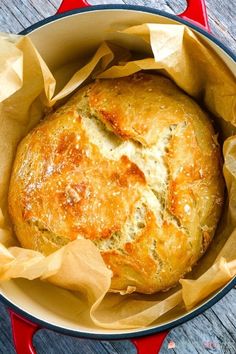 a baked bread in a red pot on a wooden table