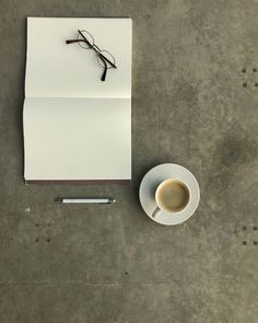 a cup of coffee next to a piece of paper and eyeglasses on a table