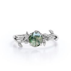 a ring with leaves and a green stone in the center, on a white background