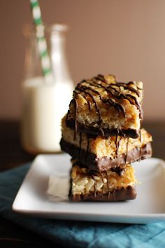 three pieces of chocolate covered dessert sitting on a plate next to a glass of milk