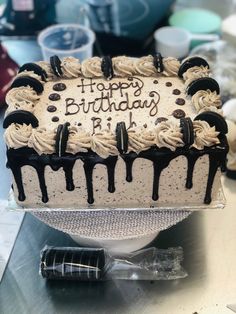 a birthday cake with white frosting and chocolate drips on it sitting on a table