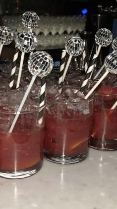 there are many cocktails on the table with lollipop sticks sticking out of them