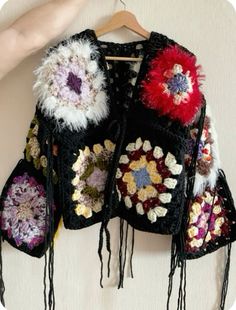 a black jacket with flowers and fringes hanging on a wall