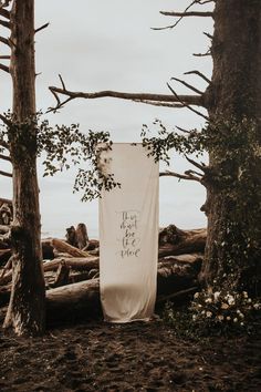 a white banner with the words let us be true on it in front of some trees