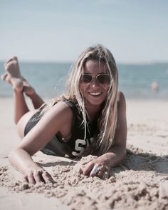 a woman laying on top of a sandy beach