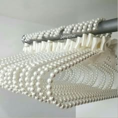 three different types of brushes are hanging from the ceiling with pearls on them and one is white