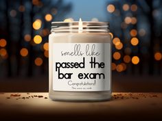 a candle that reads, smell like passed the bar exam congratulations on it with boke lights in the background