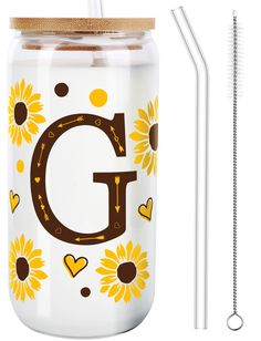 a glass mason jar with sunflowers and the letter g on it next to a straw