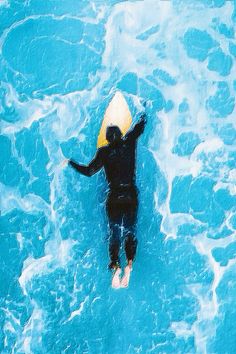 a man riding on top of a surfboard in the middle of blue ocean water