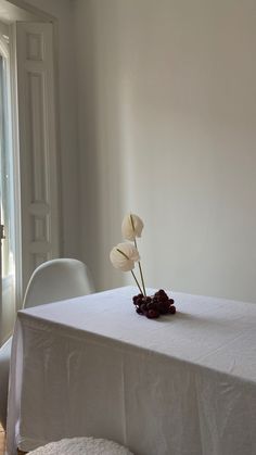 a white table with three flowers on it