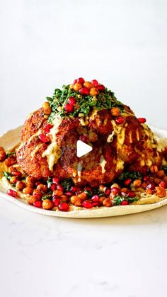 a white plate topped with meat covered in sauce and garnished with pomegranates