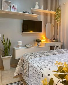 a bedroom with a bed, dresser and television on the wall above it is decorated in black and white polka dots