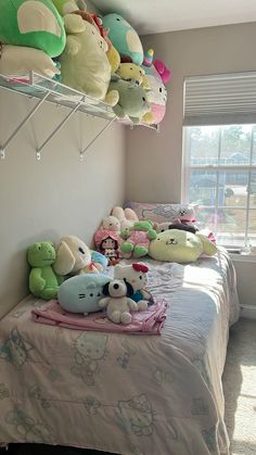 there are many stuffed animals on the shelf above the bed in this room, and one is laying down