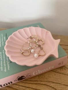 a pink plate with pearls on it sitting on top of a table next to a book