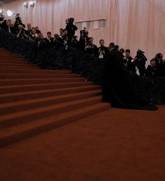 a group of people standing on top of a red carpeted staircase next to each other