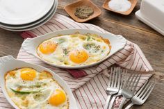 two plates with eggs on them sitting next to silverware and utensils,