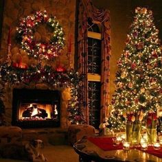 a living room decorated for christmas with lit trees and candles in front of the fireplace