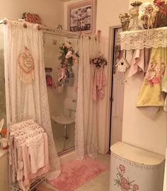 a white bathroom with pink rugs and curtains