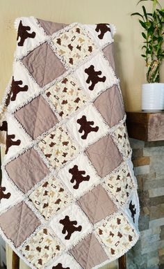 a teddy bear quilt on a chair next to a potted plant