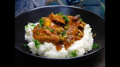 a black plate topped with mashed potatoes covered in meat and gravy next to a stuffed animal