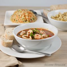 there is a bowl of soup with shrimp and rice on the table next to it