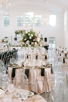 the tables are set up with clear chairs and centerpieces for an elegant wedding reception