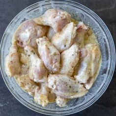 a glass bowl filled with chicken on top of a table