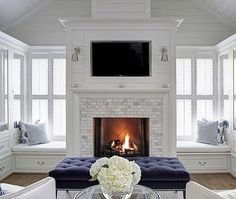 a living room filled with furniture and a fire place in front of a tv mounted on the wall