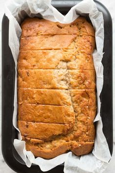 a loaf of bread sitting in a pan on top of parchment paper next to a knife