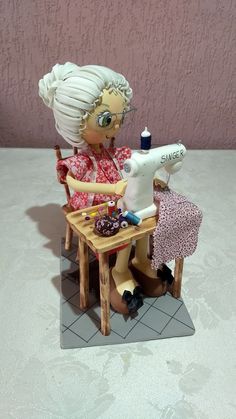 a figurine sitting at a table with a sewing machine on top of it