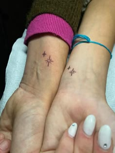 two people with matching tattoos on their wrists, one has a cross and the other has a star