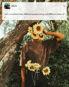 a man with sunflowers on his head standing in front of a tree