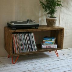 a record player sitting on top of a wooden shelf next to a potted plant