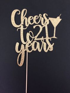 a cake topper that says cheers twenty years on it with the number twenty in gold glitter