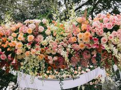 an arrangement of flowers hanging from the ceiling at a wedding ceremony with white draping