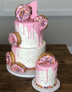 a three tiered cake with pink frosting and sprinkles on it