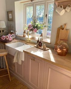 a kitchen filled with lots of counter space and flowers on the window sill over the sink