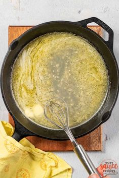 a skillet filled with liquid and whisk on top of a wooden cutting board