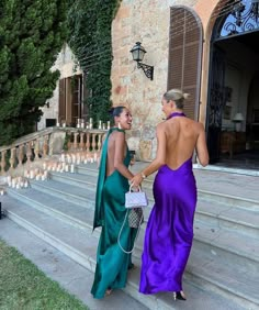 two women in long dresses walking up some steps