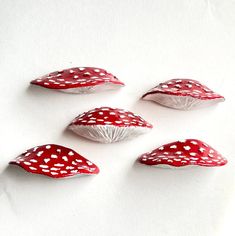 four red and white mushrooms sitting on top of a white countertop next to each other