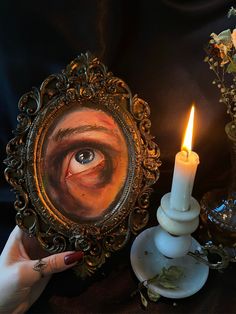 a person holding up a mirror with a candle in front of it and an image of a man's eye