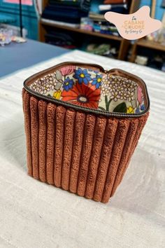 a brown purse sitting on top of a bed next to a book shelf with books