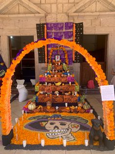 a decorated altar with candles and decorations on the floor in front of a wall that reads, day of the dead