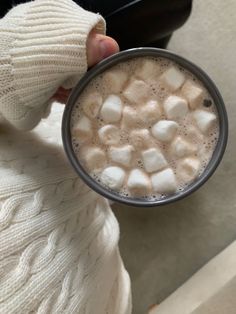 someone holding a cup of hot chocolate with marshmallows in it