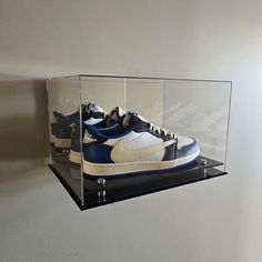 a pair of sneakers are in a clear case on the side of a white wall