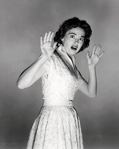 an old photo of a woman in a dress with her hands up to the side